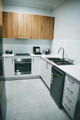 a kitchen with white counters and a sink and a dishwasher at CocoBrew Boutique Apartments in Rockhampton