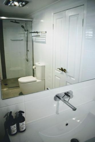 a bathroom with a sink and a toilet and a mirror at CocoBrew Boutique Apartments in Rockhampton