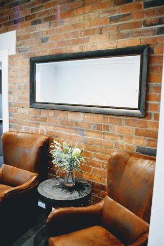 a brick wall with a mirror and two chairs and a table at CocoBrew Boutique Apartments in Rockhampton