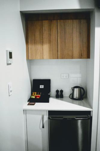 a kitchen with a black refrigerator and wooden cabinets at CocoBrew Boutique Apartments in Rockhampton