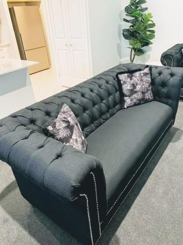 a black leather couch with two pillows on it at CocoBrew Boutique Apartments in Rockhampton