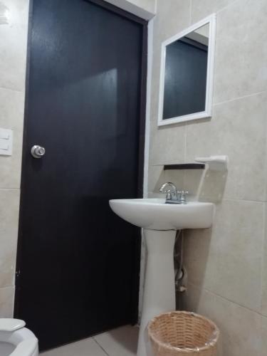 a bathroom with a sink and a black door at Kali Huasteca Posada in Ciudad Valles