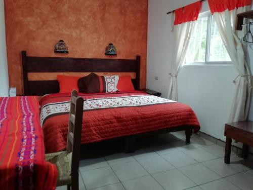 a bedroom with a bed with red sheets and a window at Kali Huasteca Posada in Ciudad Valles
