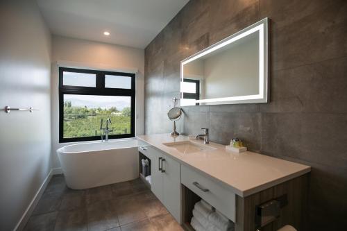 bagno con vasca, lavandino e finestra di The Inn at Therapy Vineyards a Naramata