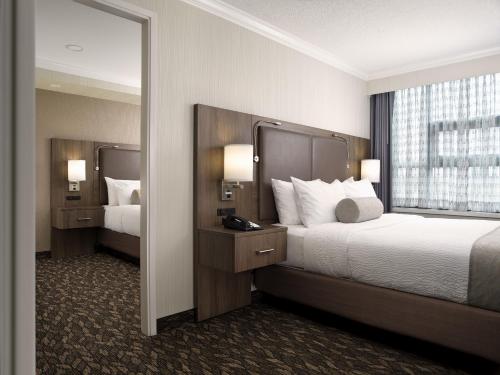 a hotel room with two beds and a mirror at BEST WESTERN PLUS Carlton Plaza Hotel in Victoria