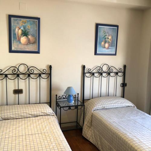 two beds in a bedroom with two pictures on the wall at La casa de Tita Elvira 2 in Zafarraya