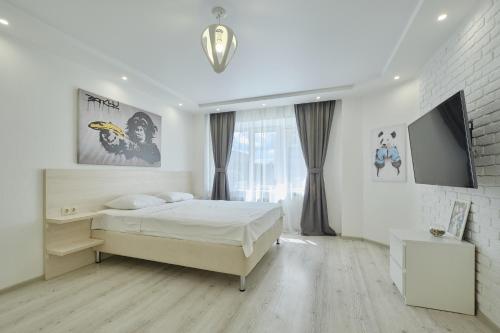 a white bedroom with a bed and a tv at Apartment Petrovskie on Frunze 46 in Tomsk