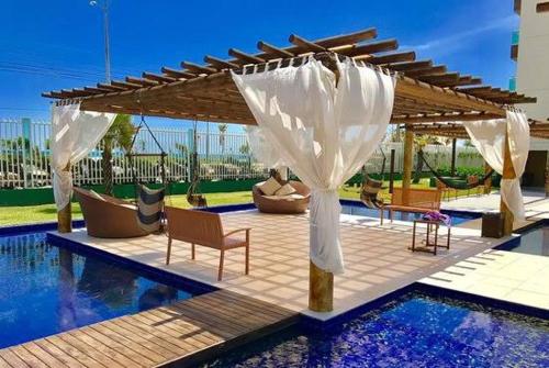 a pergola over a swimming pool with chairs at vgfun S flats in Fortaleza