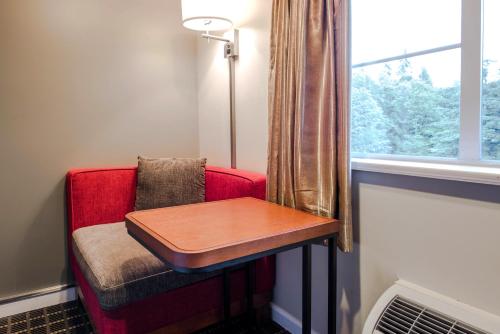 a red chair with a table next to a window at Gibsons Garden Hotel in Gibsons