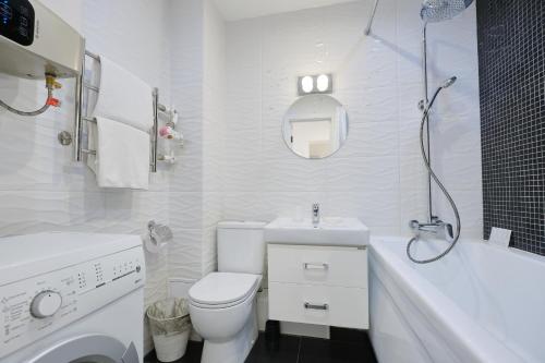 a white bathroom with a toilet and a sink at Apartment Petrovskie on Frunze 46 in Tomsk