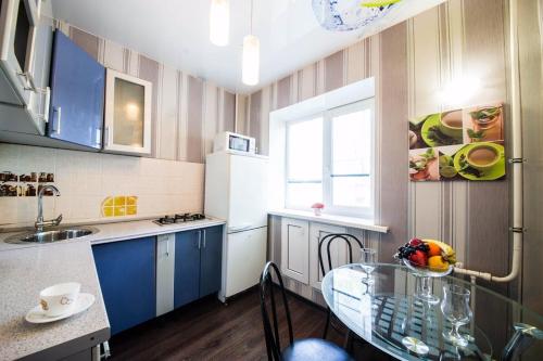 uma pequena cozinha com uma mesa de vidro e armários azuis em 2-х комнатная квартира на Набережной em Saratov