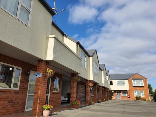 a row of houses with potted plants on a street at Rosewood Court Motel in Christchurch