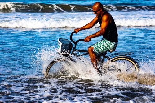 a man riding a bike in the water at Le Cameleon Boutique Hotel in Puerto Viejo