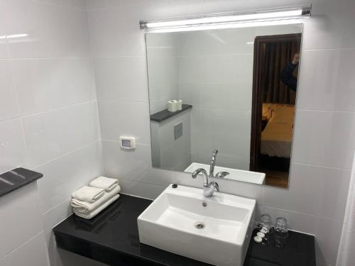 a white bathroom with a sink and a mirror at Berger Hotel in Tiberias