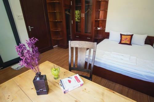 a room with a bed and a table with a vase of flowers at Nhà của Elly in Da Nang