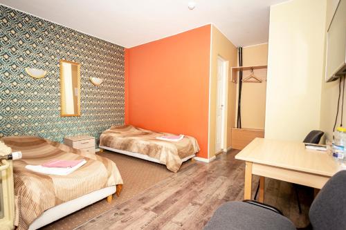 two beds in a room with orange walls and wooden floors at Guest House Rannaliiv in Võsu