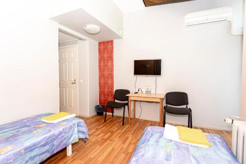 a bedroom with two beds and a desk with chairs at Guest House Rannaliiv in Võsu
