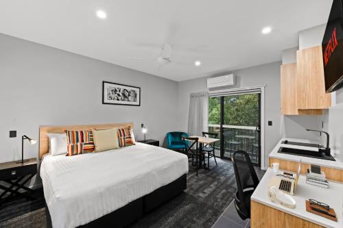 a hotel room with a bed and a desk and a kitchen at AVENUE MOTEL APARTMENTS in Toowoomba