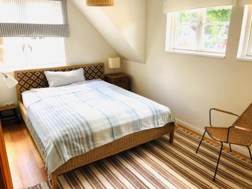 um quarto com uma cama, uma cadeira e 2 janelas em Katjas Kate em Prerow