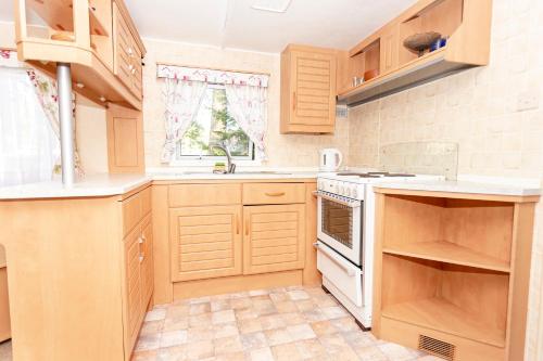 a kitchen with wooden cabinets and a white stove top oven at Guest House Rannaliiv in Võsu