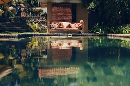 une personne assise sur un canapé à côté d'une piscine dans l'établissement Aga Surf View, à Tangalle