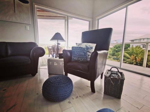 a living room with a chair and a couch and windows at The Blue Dragonfly in Jeffreys Bay