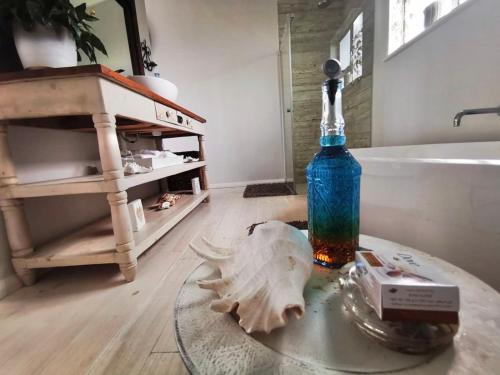 a glass table with a bottle and a skull on it in a bathroom at The Blue Dragonfly in Jeffreys Bay