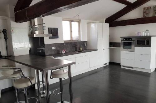 une cuisine avec des armoires blanches et une table et des chaises dans l'établissement L'Escapadou - Charme et Tranquillité, à Albi