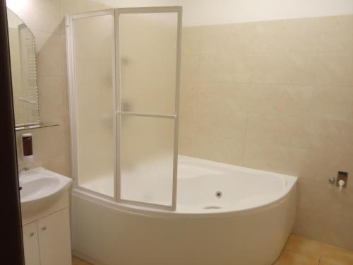 a white bathroom with a tub and a sink at Pension Fontána Svitavy in Svitavy