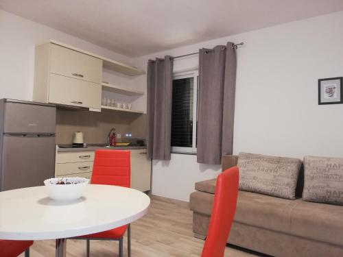 a living room with a white table and red chairs at Mitan apartman in Tučepi