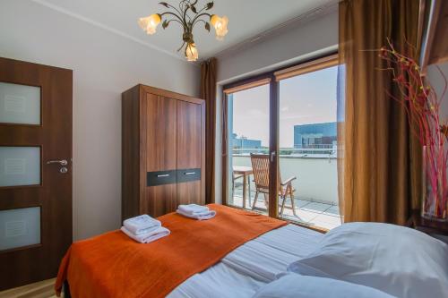 een slaapkamer met een bed met uitzicht op een balkon bij Osiedle Platan - Apartamenty Bryza - Centrum in Świnoujście