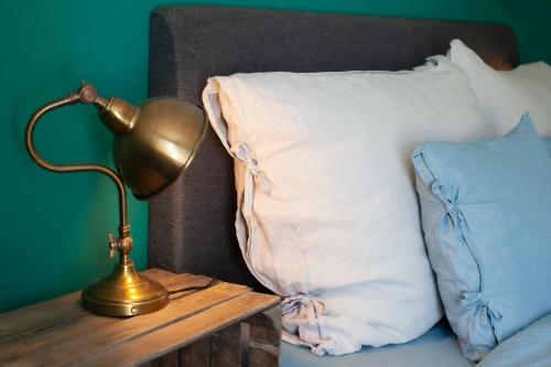 a gold lamp on a wooden table next to a pillow at Three Pheasants Boutique Bed and Breakfast in Ekeby