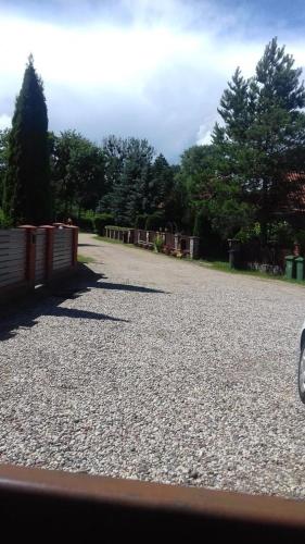 a gravel road with a fence and trees at Zbychówka in Kolonia Rybacka