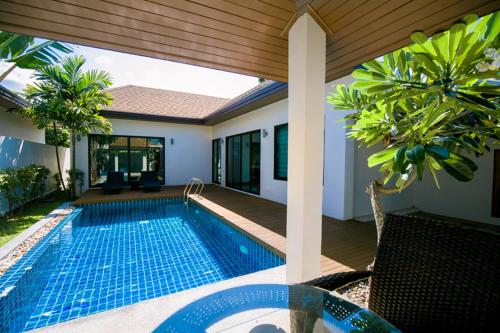 a swimming pool in front of a house at Thaiya Pool Villa in Ban Klang