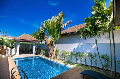 uma piscina em frente a uma casa com palmeiras em Thaiya Pool Villa em Ban Klang