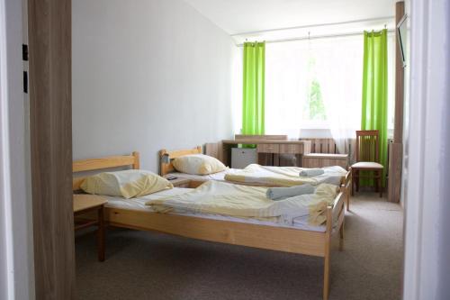two beds in a room with green curtains at Prima in Krynica Morska