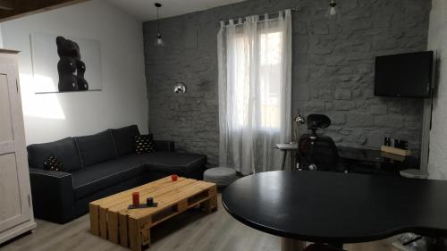 a living room with a black couch and a table at Duplex au Coeur de Lunel in Lunel
