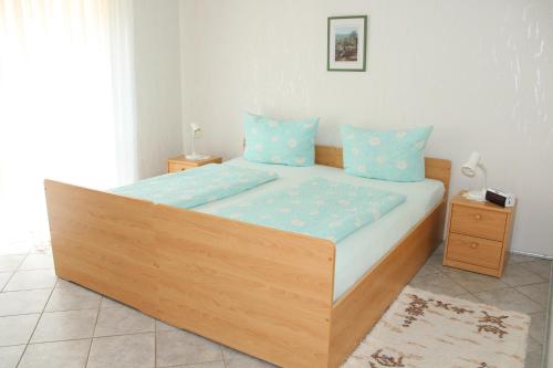 - une chambre avec un grand lit en bois et des oreillers bleus dans l'établissement Haus am Fürstenweg, à Neustadt an der Weinstraße