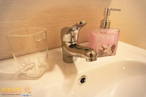 a sink with a soap dispenser and a glass on it at Balti Domki Letniskowe in Dębina