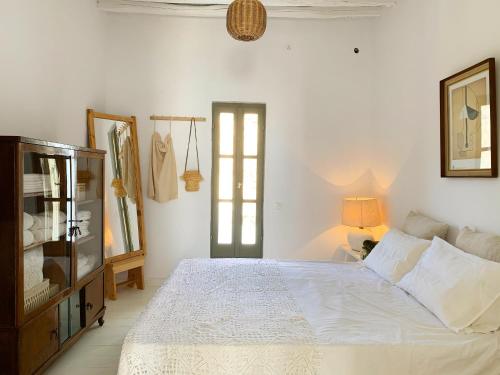 ein weißes Schlafzimmer mit einem Bett und einem Fenster in der Unterkunft Serifos Olive in Serifos Chora