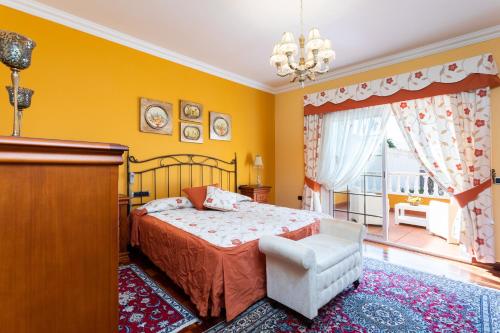een slaapkamer met een bed, een stoel en een raam bij Home2Book Luxury El Helecho del Teide, Private Pool in Tacoronte