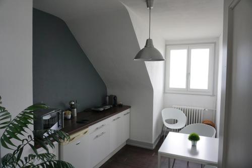 a kitchen with white cabinets and a table and a window at Studio Maujobia 31 in Neuchâtel