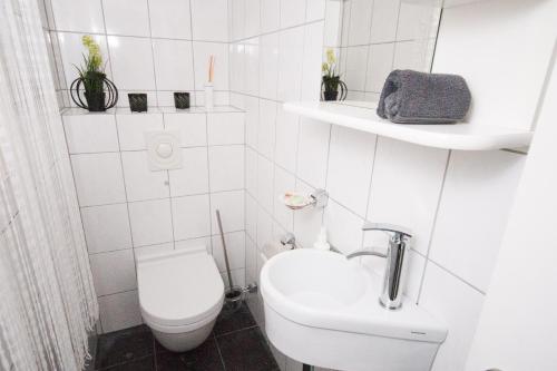 Baño blanco con aseo y lavamanos en Heidehaus Lippl am Steinhuder Meer, en Rehburg-Loccum