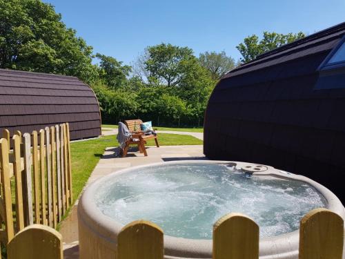 a hot tub in a backyard with a bench at Ribblesdale Pods in Horton in Ribblesdale