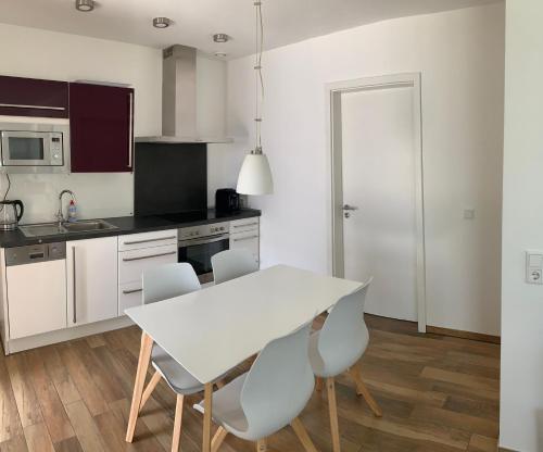 a white kitchen with a white table and chairs at 2-Zimmer-Wohnung bei Nürnberg mit S-Bahn-Anschluss in Postbauer-Heng