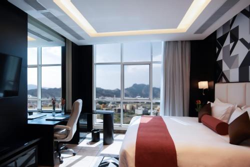 a hotel room with a bed and a desk and a window at Bayat Suites in Muhayil
