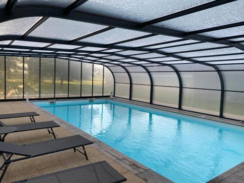 an indoor swimming pool with a glass ceiling at Moulin d'Amour in Chambon