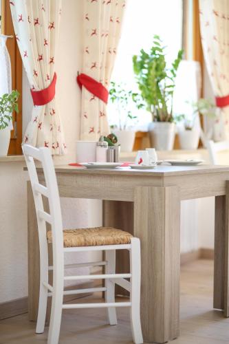 a table with a white chair and a table with plants at Landhaus Schwaben in Bad Wiessee