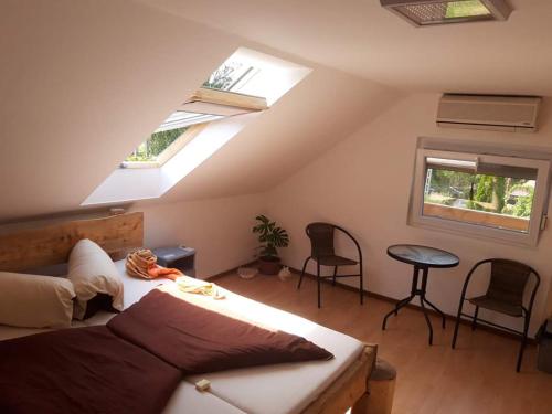 1 dormitorio con 1 cama y algunas ventanas y sillas en Margaréta Étterem és Vendéghàz Gasthaus, en Balatonberény