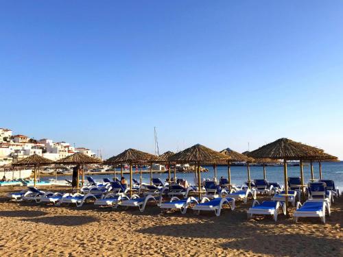 a group of lounge chairs and umbrellas on a beach at Erato Apartments in Batsi